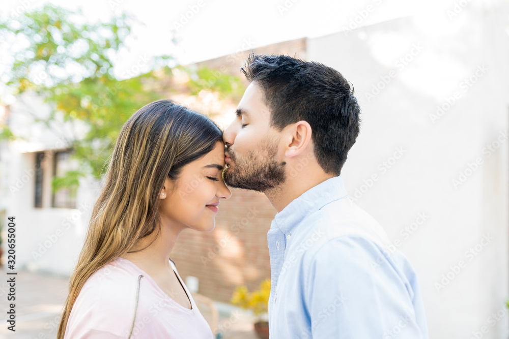 Man Kissing Forehead Of Girlfriend Outside Cafe Man Kissing Forehead Of Girlfriend Outside Cafe