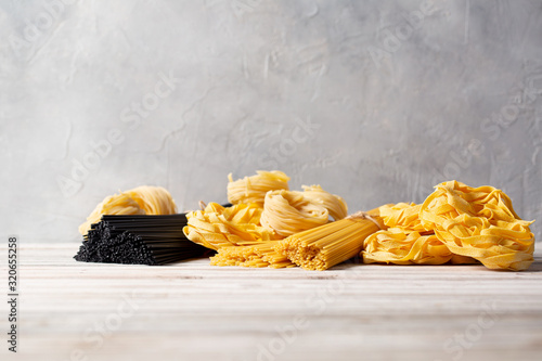 Variety of types and shapes of Italian fresh dry pasta on wooden table. Space for text. photo