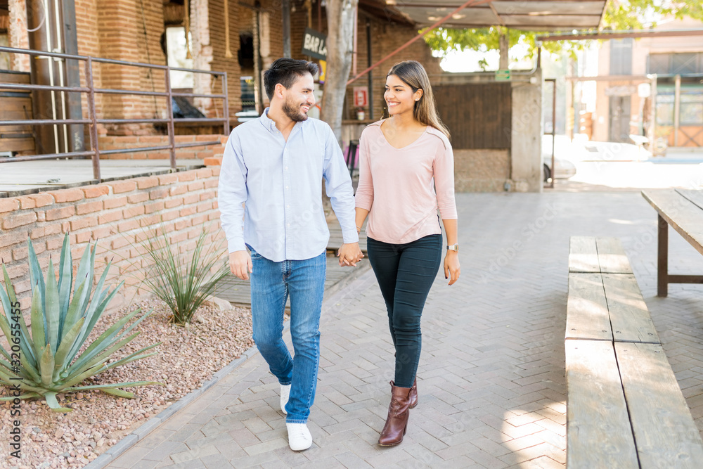 Smiling Latin Couple Walking On Footpath