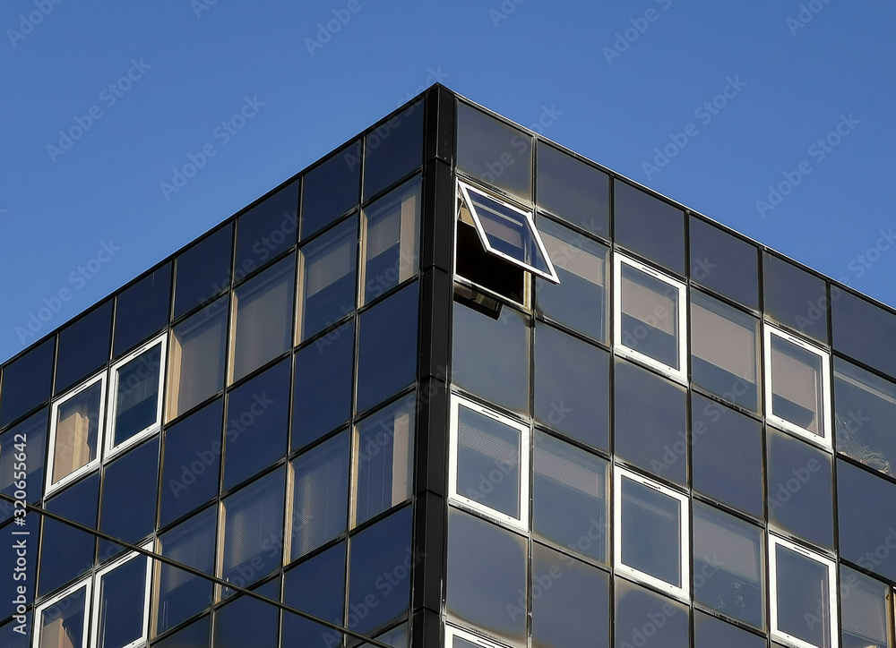 Modern building with open and closed windows against blue sky Modern building with open and closed windows against blue sky