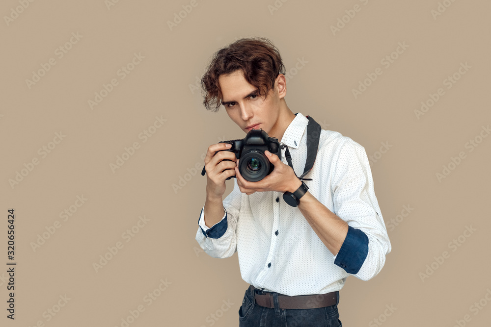 Freestyle. Stylish photographer standing isolated on gray taking photo on camera pensive Freestyle. Stylish photographer standing isolated on gray taking photo on camera pensive