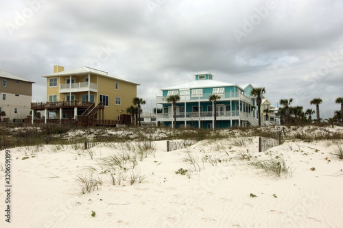 Travel America and visit Alabama background.Cloudy seascape with freshly built after hurricane colorful houses for vacation rentals and white sand in a foreground. Alabama Gulf Shores beach area, USA.