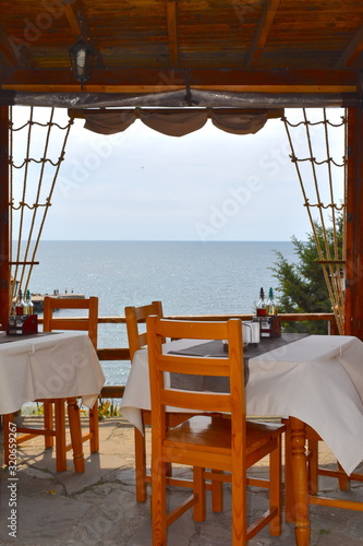 Traditional Bulgarian sea view a la carte fish restaurant outdoor terrace in summer resort Tables ready to welcome hungry couples and families with kids who will order specialties on the dinner menu