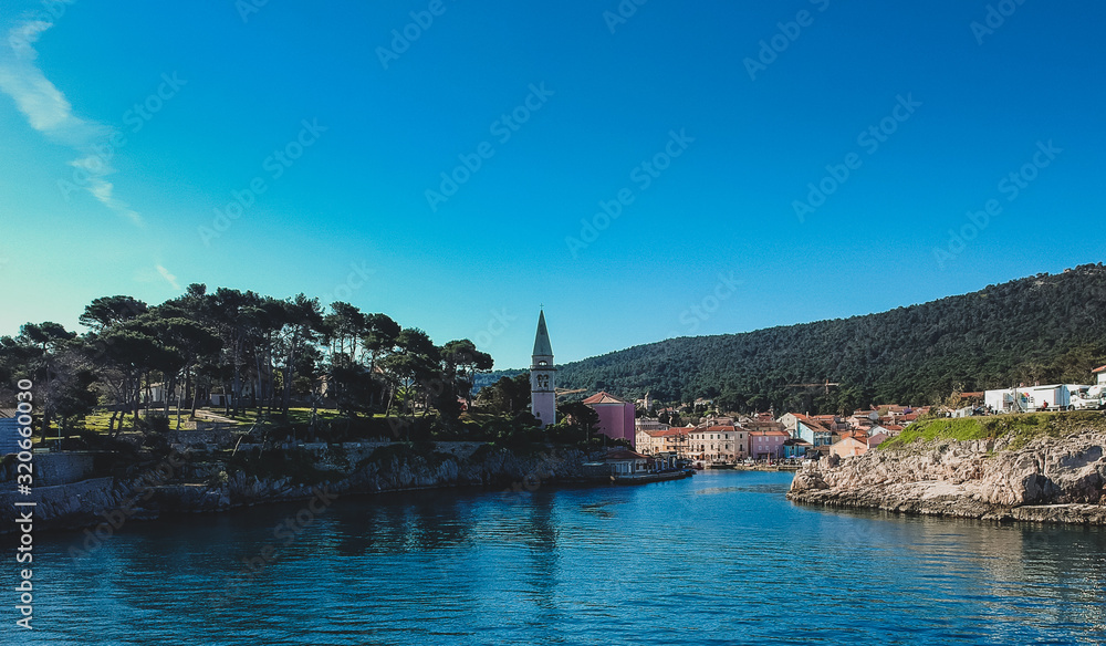 Panoramic aerial photo of the village of Veli Losinj in the Croatian island. View towards the port or marina of the village. Beautiful colorful houses and church are seen.