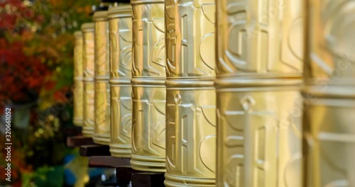 Bhuddhist prayer wheel golden inscribed with a sanskrit prayer and creamy bokeh . photo