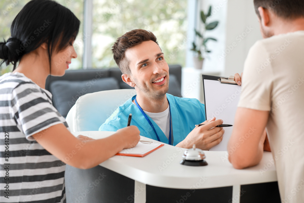 Male receptionist working with patients in clinic Male receptionist working with patients in clinic