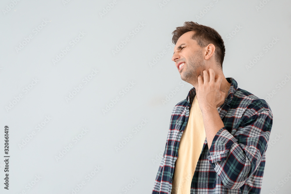 Scratching allergic man on light background Scratching allergic man on light background