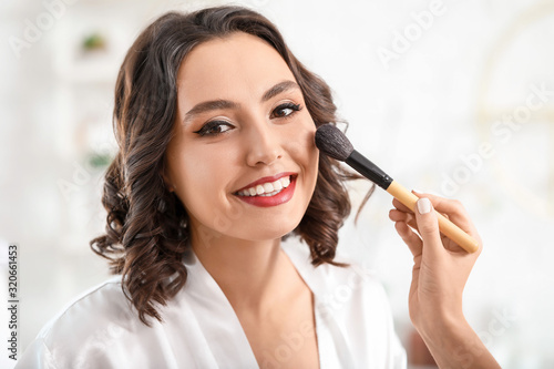 Makeup artist working with beautiful young woman in salon