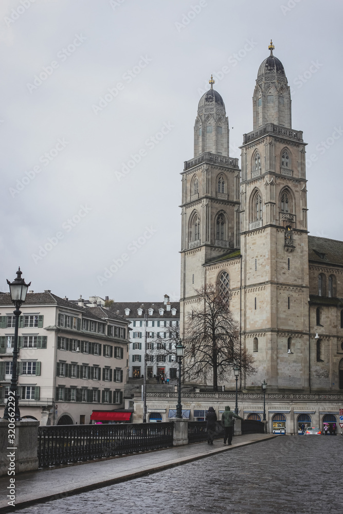Vertical photo of Grossmunster church and a part of Zurich old town in a cold, cloudy winter like environment.