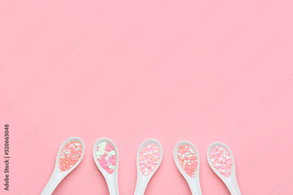 Spoons with glitters on pink background