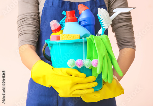 Janitor with set of cleaning supplies on color background, closeup