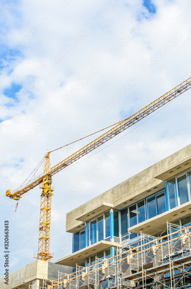 High-rise building under construction. The site with cranes against blue sky High-rise building under construction. The site with cranes against blue sky