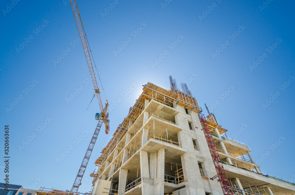 High-rise building under construction. The site with cranes against blue sky