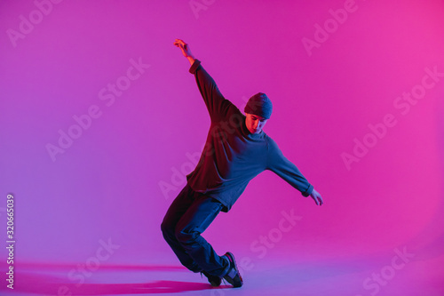 Young Man in a Jumper Dancing Contemporary Dance in Studio. Breakdancing. Dance School Poster. Copy Space. Battle competition announcement. Pink and Blue Background. photo