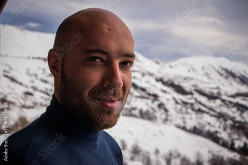 Portrait of a young man standing in front of a french alpine background. High altitude portrait of a man in technical sports clothing.