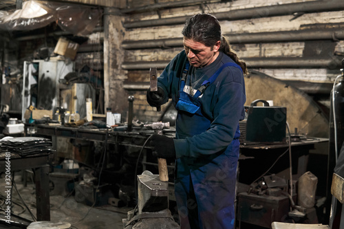 blacksmith straightens a hammer in a forge