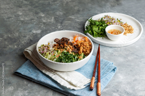 bowl of traditional Vietnamese noodle salad - Bun Bo Nam Bo, with beef, rice noodles, fresh herbs, pickled vegetables and fish sauce photo