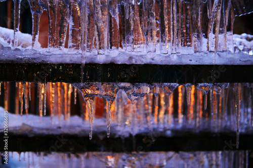 winter background - icicles on an outdoor staircase lit by a window behind it