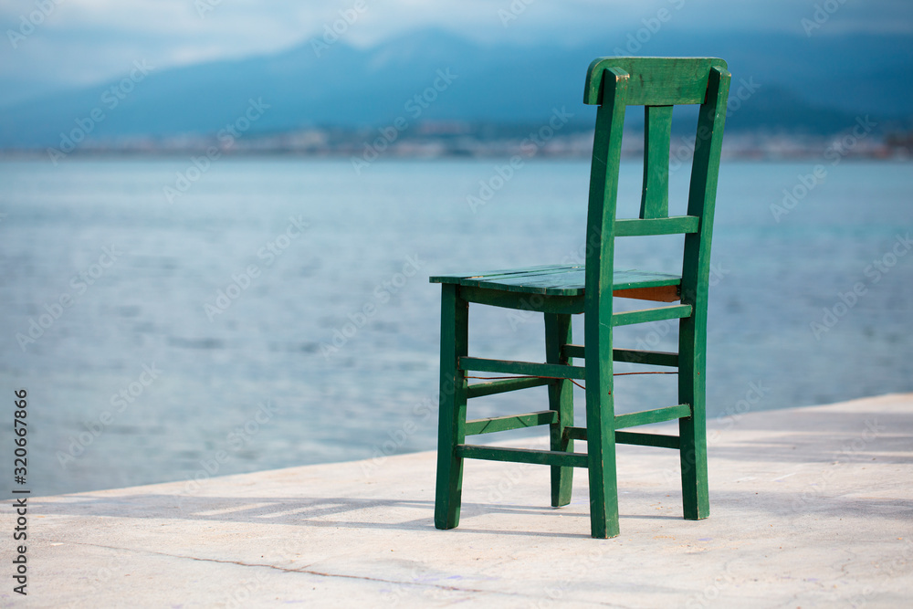 old chair on the sea shore, dramatic sky, melancholic scene, loneliness