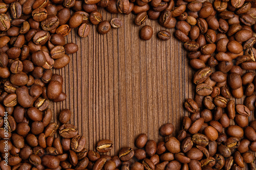 Roasted coffee beans create a circle for copy space on the background of burnt wooden background.