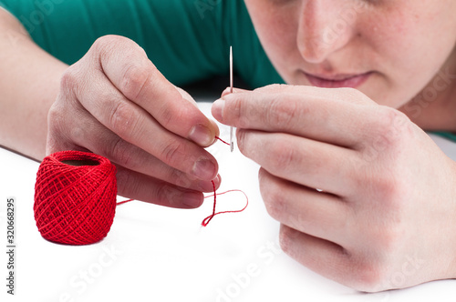 Needle and thread in woman's hand isolated on white background.Copy space