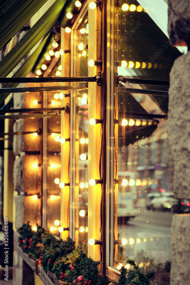 Obraz premium The facade of the restaurant building is decorated with lights. vertical.