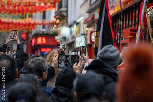 people on the street taking photographs with their smartphone during the chinese new year