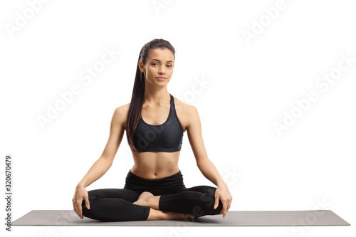 Young female in sportswear sitting on a mat with crossed legs