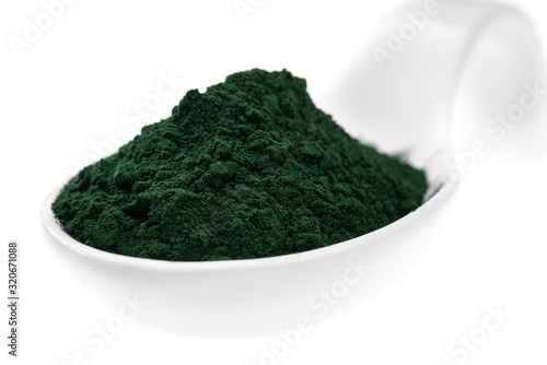 Vitamin and mineral supplements for vegetarians spirulina powder in a ceramic spoon, close-up.