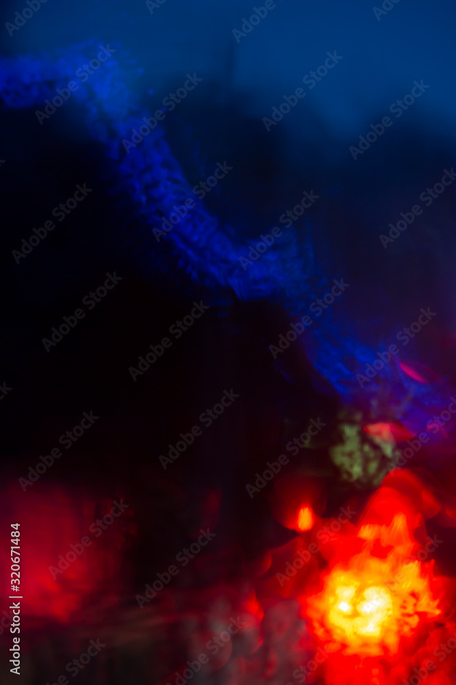 Fototapeta premium abstract bokeh caused by rain drops reflecting onto car windscreen from car brake lights and city street bridge lights on dusk. Indistict focus applied.
