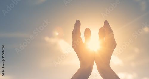 Woman hands holding the sun at dawn. Freedom and spirituality concept. 