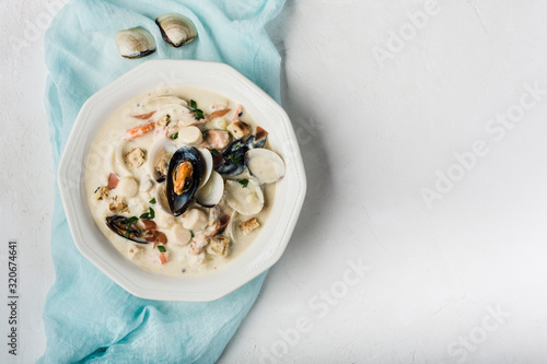 Clam chowder in a white plate. The main ingredients are shellfish, broth, butter, potatoes and onions. photo