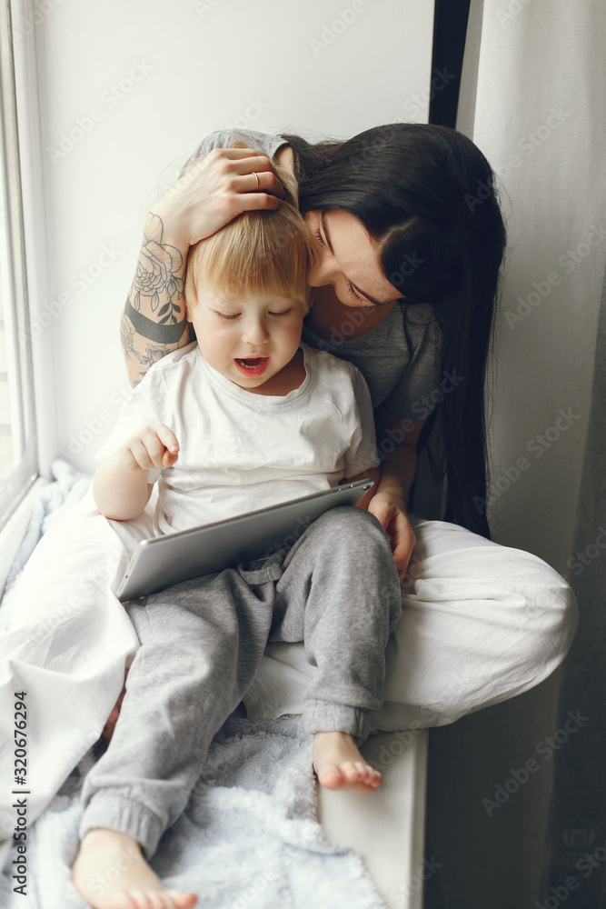 Beautiful woman with child. Woman in a gray t-shirt. Family sitting on a windowsill. Beautiful woman with child. Woman in a gray t-shirt. Family sitting on a windowsill.