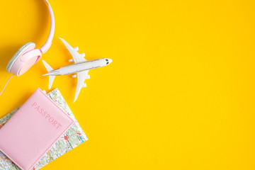 Airplane travel concept. Flat lay traveler accessories on yellow background with copy space. Top view plane, passport, map, headphones. Travel agency banner design template