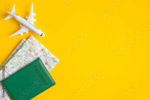 Summer travel concept. Flat lay traveler accessories on yellow background with copy space. Top view plane, passport, map. Travel agency banner design template