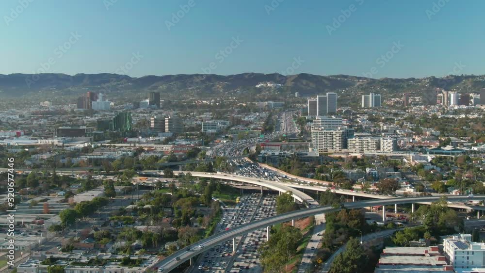 Aerial view of freeway and interstate road traffic at I-405 and I-10 intersection in urban West Los Angeles with cars below on a sunny day. Aerial view of freeway and interstate road traffic at I-405 and I-10 intersection in urban West Los Angeles with cars below on a sunny day.