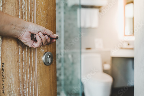 human's hand opened wooden door to toilet