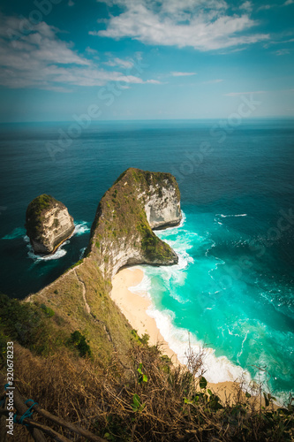 Kelingking beach or Manta bay a T-Rex head shape cliff on Nusa Penida, Bali. White sandy beach with turquoise waters enclosed by a steep cliff & headland. View from the top of the hill.