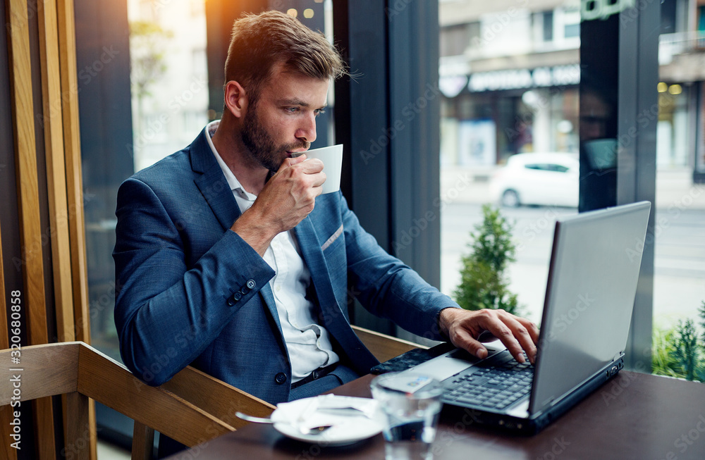 Obraz premium Business manager drinking coffee and using laptop