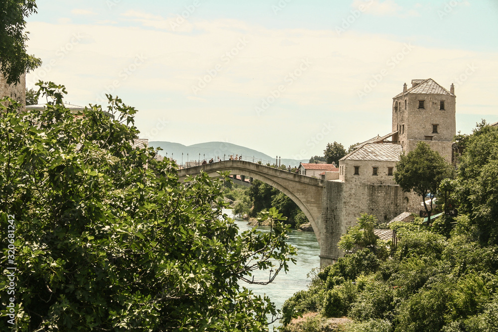 Old Bridge of Mostar during a sunny afternoon, with the old city visible in the background. This bridge is the symbol of the war torn main city of Herzegovina, in Bosnia
