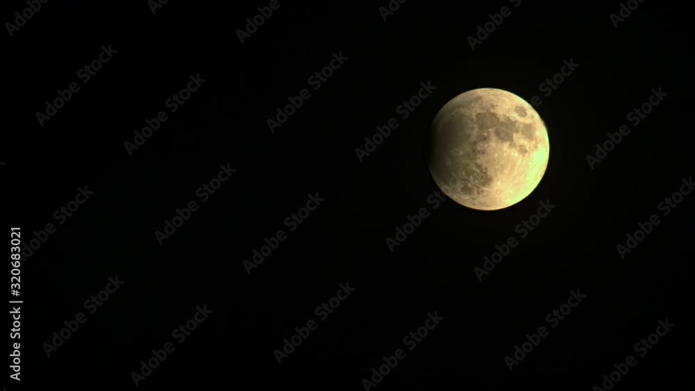 Airplane crossing a Yellow Full Moon during the initial phase of an Eclipse. Coincidence in the sky weird to see. The plane leaves a Trail in the sky
