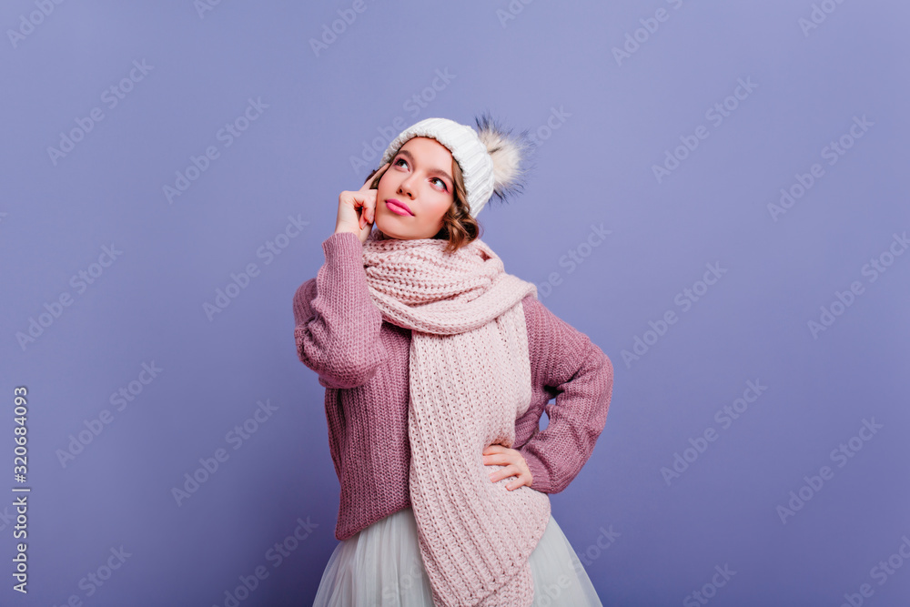 Glad caucasian woman in stylish knitted scarf posing with interest. Indoor portrait of inspired curly lady isolated on colorful background. Glad caucasian woman in stylish knitted scarf posing with interest. Indoor portrait of inspired curly lady isolated on colorful background.