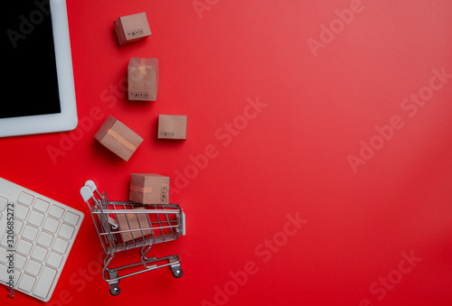 Online shopping,paper boxes,small shopping cart,smartphone and keyboard against red background