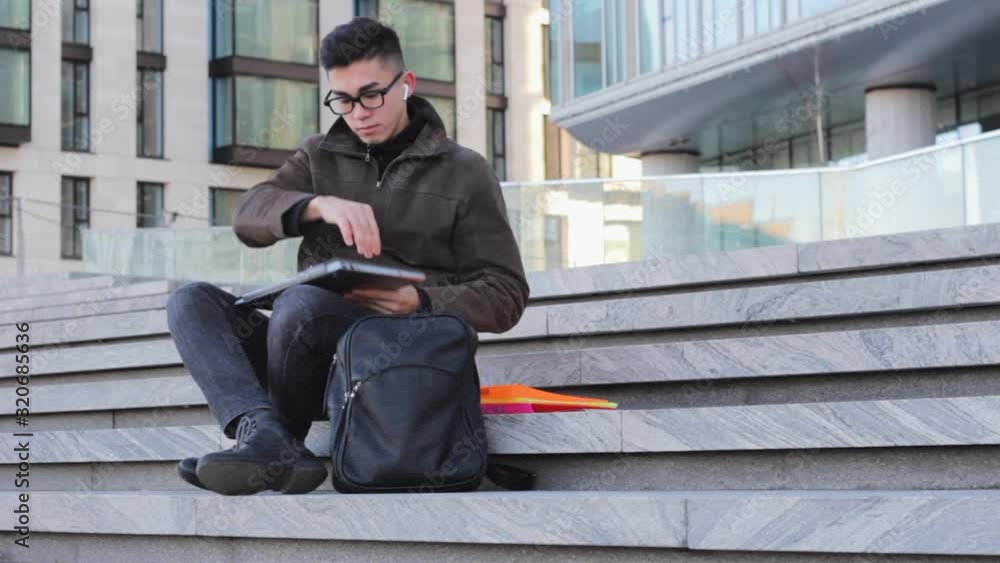 young successful Asian student programmer sit on the steps of the office building with laptop freelance young successful Asian student programmer sit on the steps of the office building with laptop freelance
