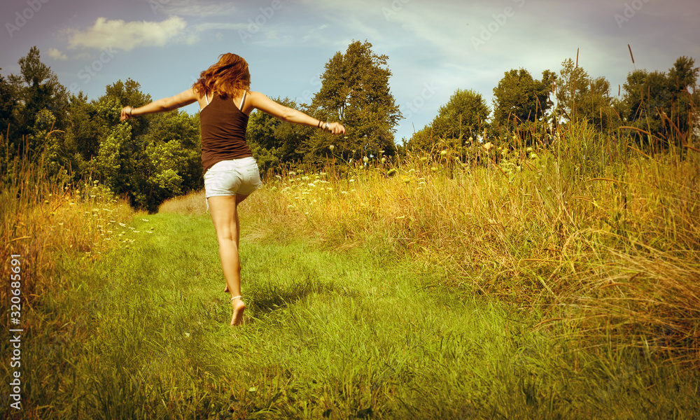 Back of young woman skipping down nature walk way Back of young woman skipping down nature walk way