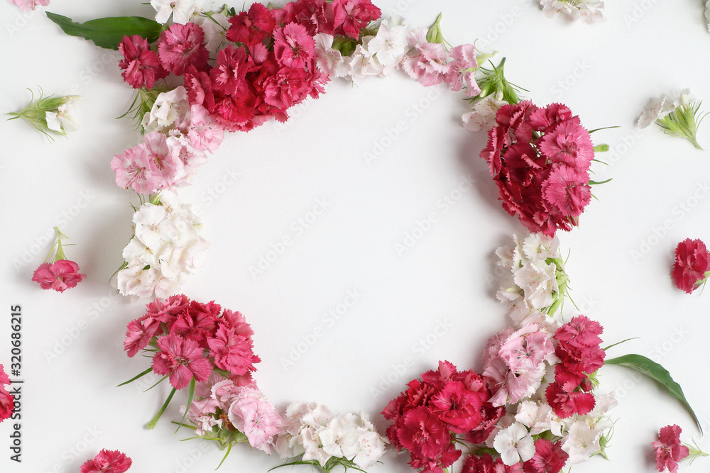 Floral arrangement with copy space. Template for greeting card or design. Frame of pink carnations on a white wooden background Floral arrangement with copy space. Template for greeting card or design. Frame of pink carnations on a white wooden background