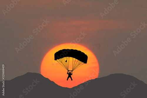  silhouettes parachuting on sunset