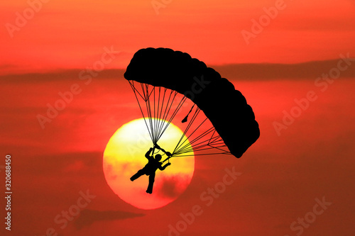  silhouettes parachuting on sunset