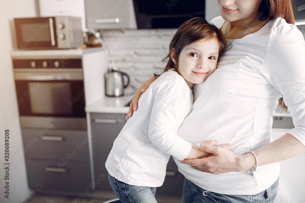 Pregnant mother with a daughter. Family in a kitchen Pregnant mother with a daughter. Family in a kitchen