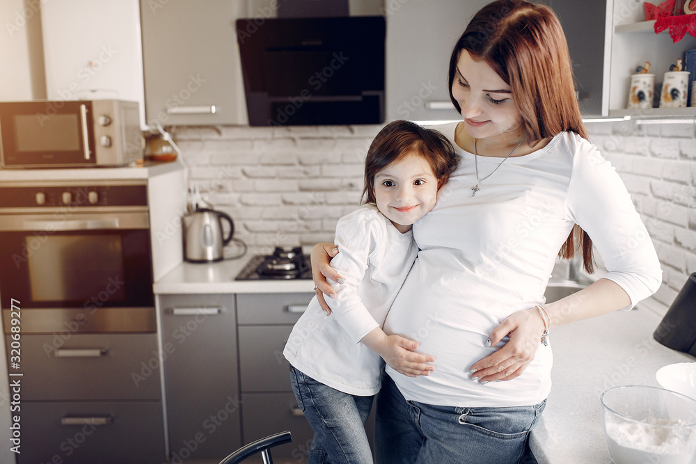 Pregnant mother with a daughter. Family in a kitchen Pregnant mother with a daughter. Family in a kitchen